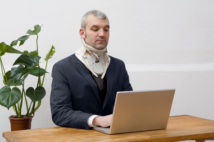 Stephen C. Carter, PC Attorney at Law | Hartwell, GA | a businessman wearing a neck brace working on his laptop